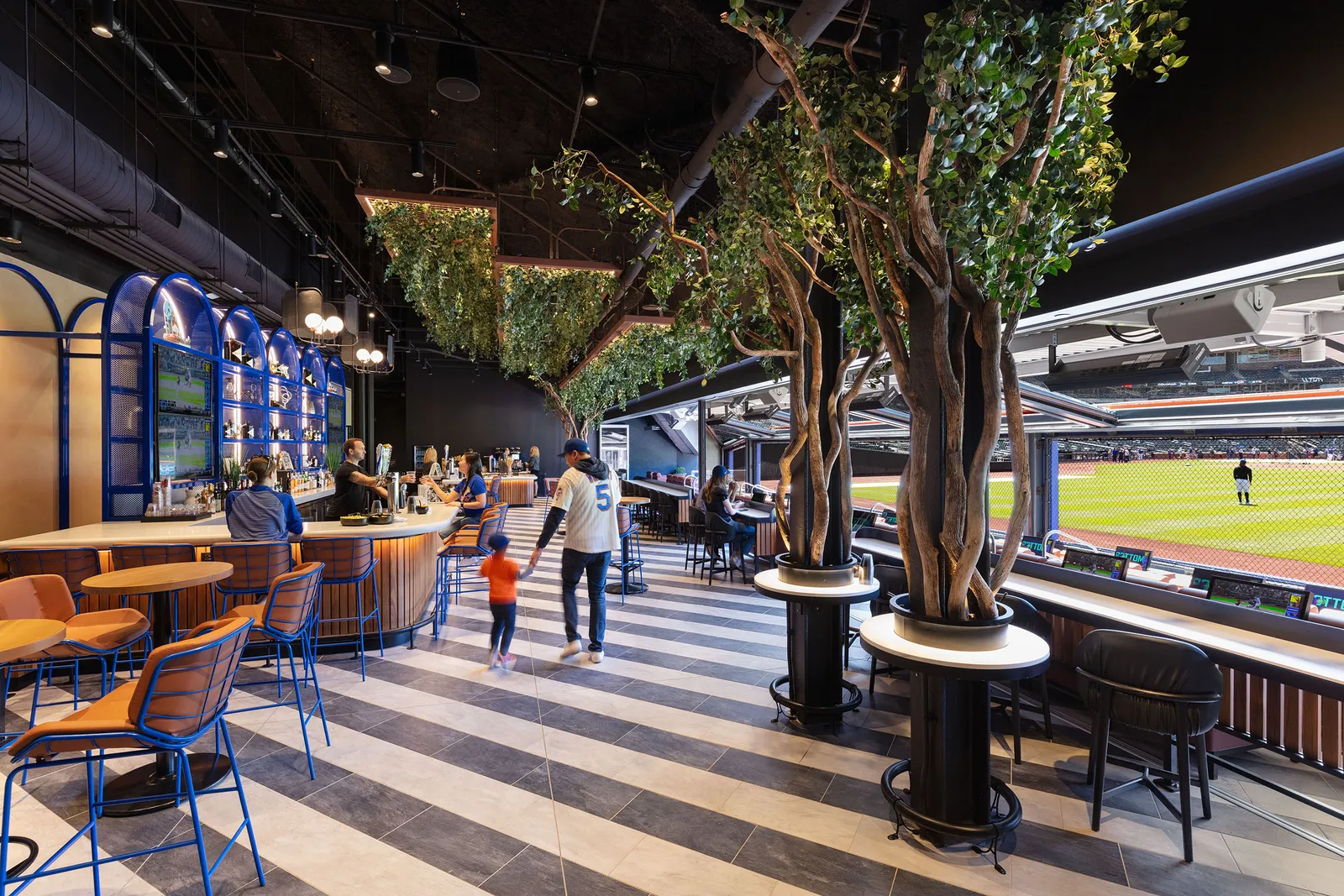 A stadium club lounge with trees planted through the bar tables