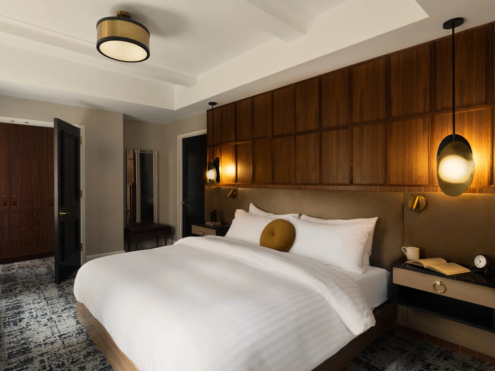 A hotel guest room with a walnut panelled wall behind the bed
