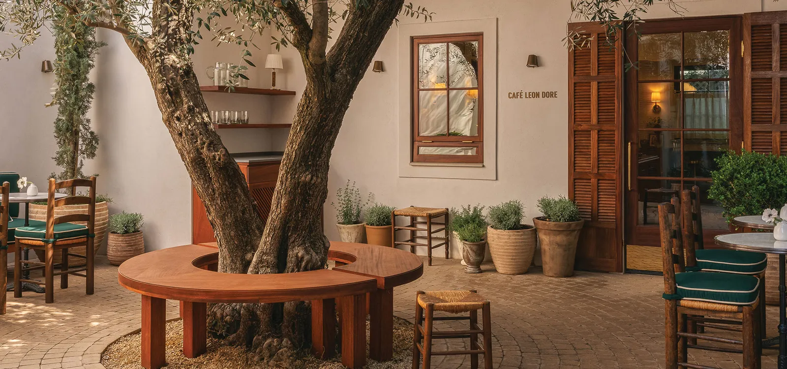 A store courtyard with an olive tree and a circular bench