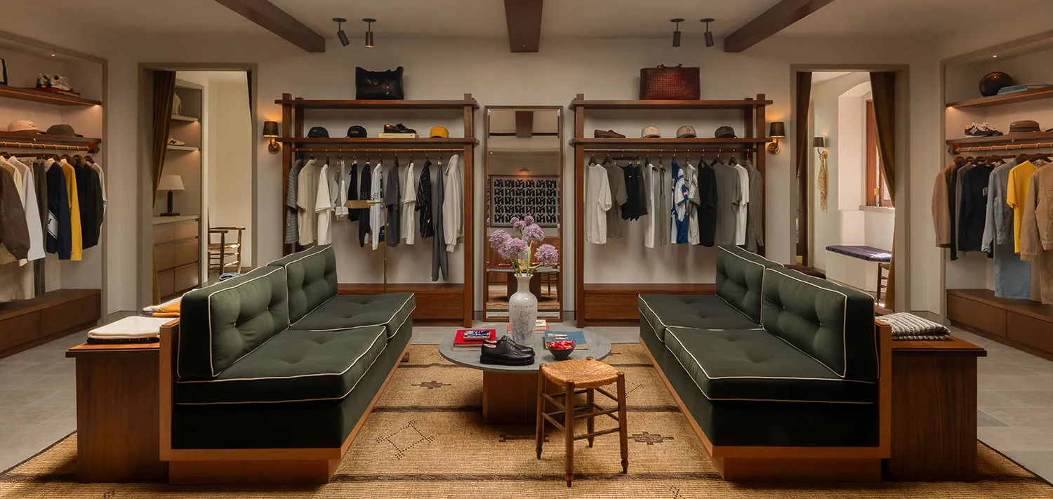 A clothing store with green banquettes and timber shelving
