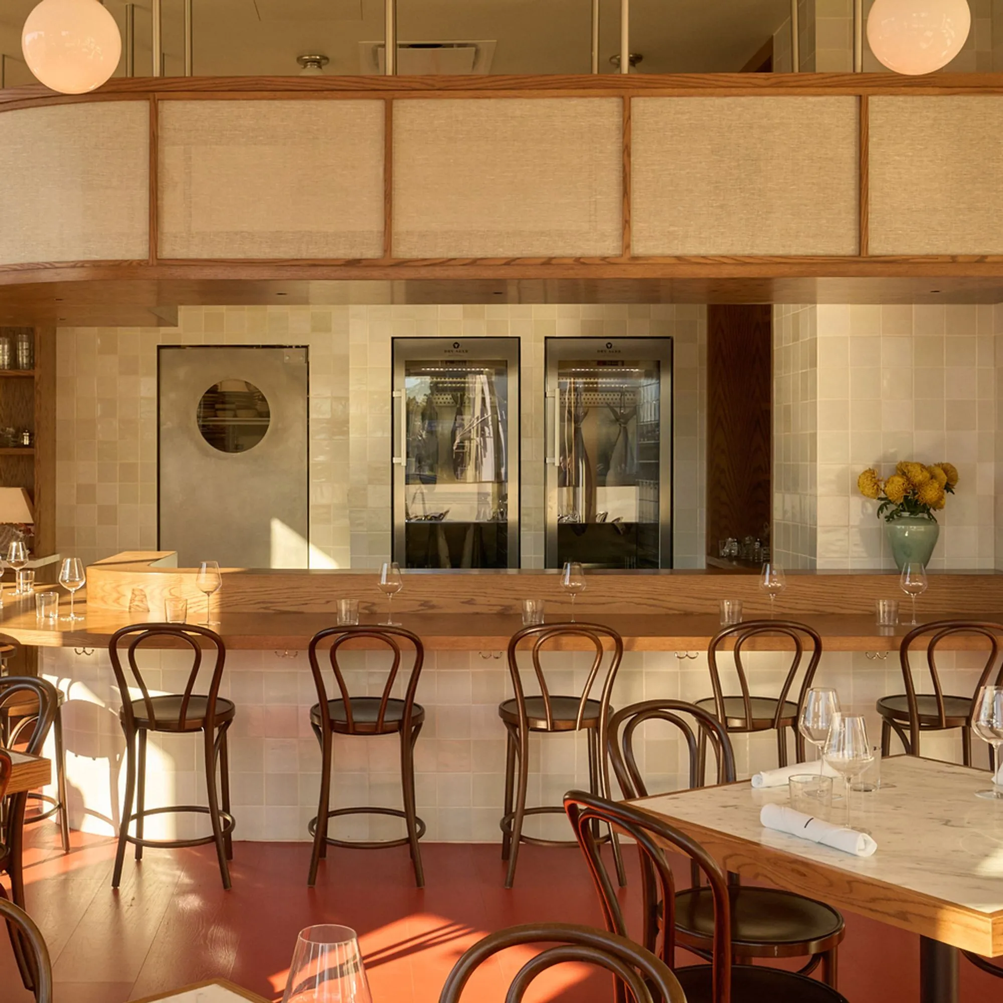 A restaurant bar with a marble counter and bentwood stools